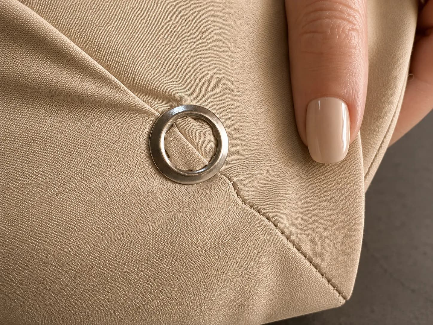 Close-up of a hand holding the sheet corner, showing the set grommet and the reinforced stitching along the hem