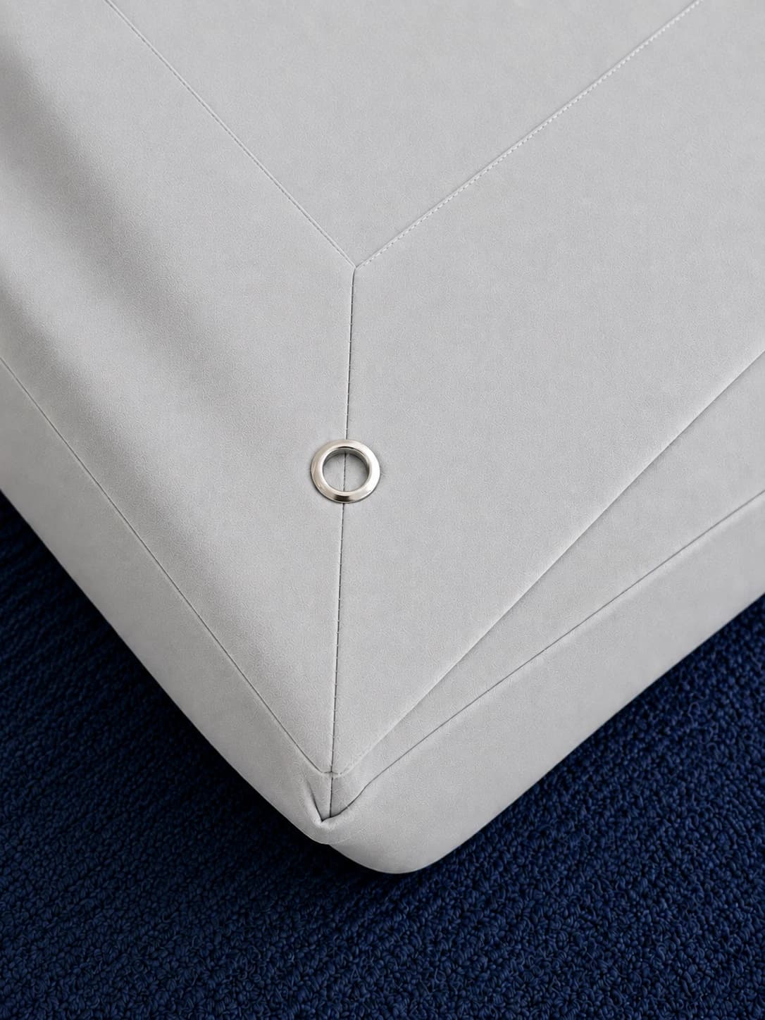 Close-up of the fitted base corner with the bottom sheet snapped into place over the grommet