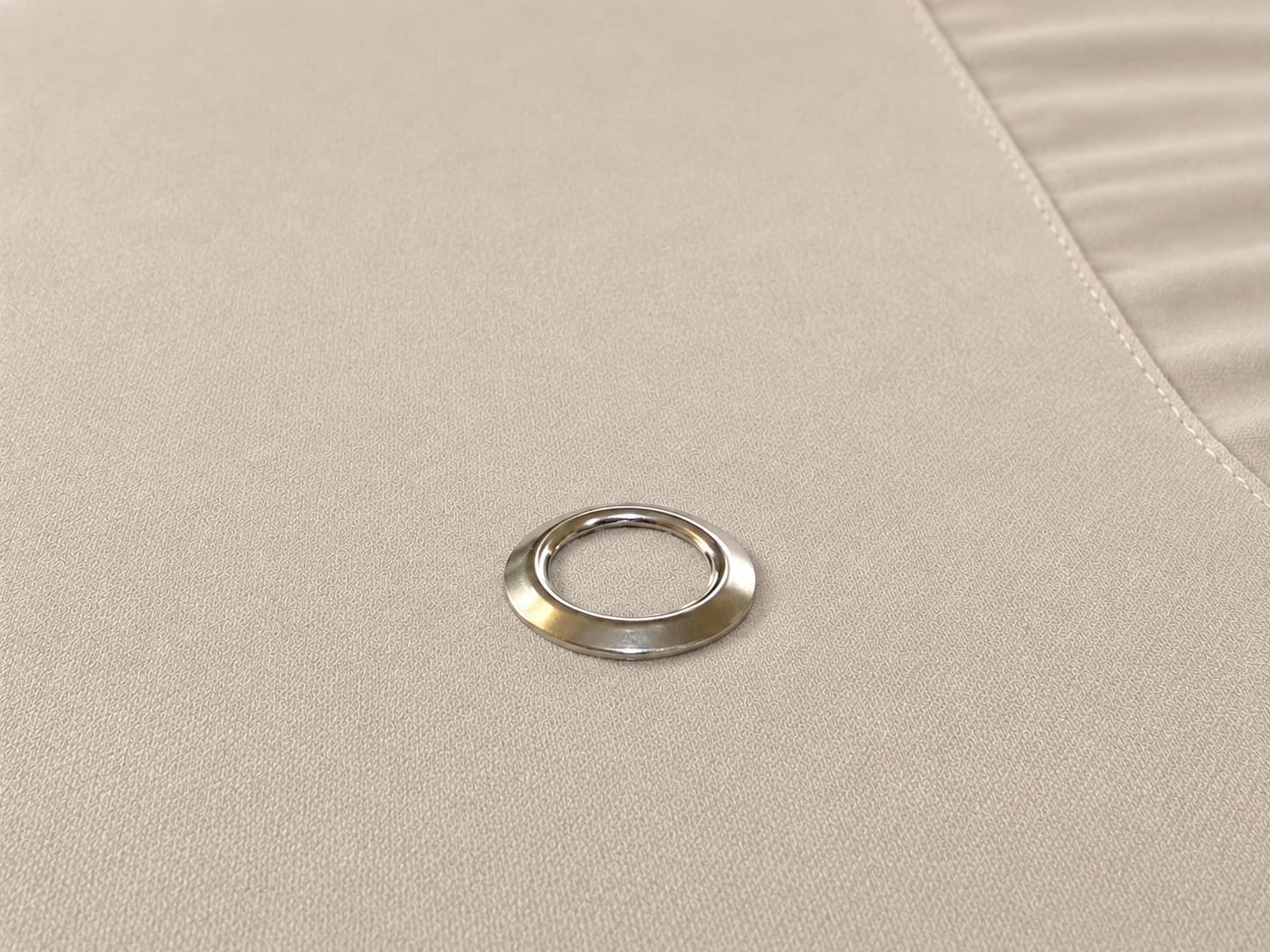 Raking close-up of a single low-profile snap sitting almost flush with the sheet surface