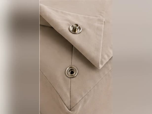 Close-up of the snap system: the stud on the bottom sheet corner aligned above the matching socket on the fitted base